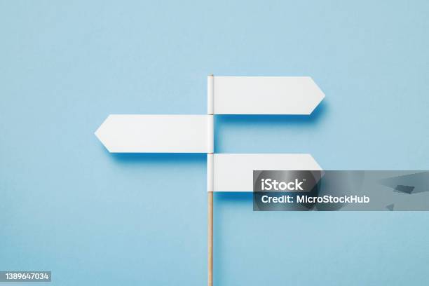 Three Directional Signs Pointing Opposite Directions Over Blue Background Stock Photo - Download Image Now