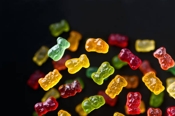 istock Multicolored flying gummy bears on a black background, flat lay 1389647529