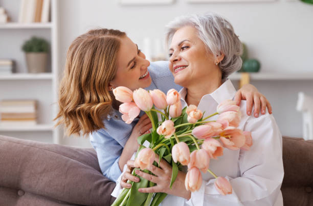 若い女性、新鮮なチューリップの花束を持って年配の母親におめでとうございます - beautiful senior woman ストックフォトと画像
