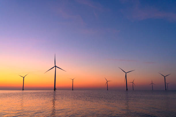 Wind turbines producing sustainable renewable energy in an offshore wind park in Flevoland, The Netehrlands, during sunset. Drone point of view.