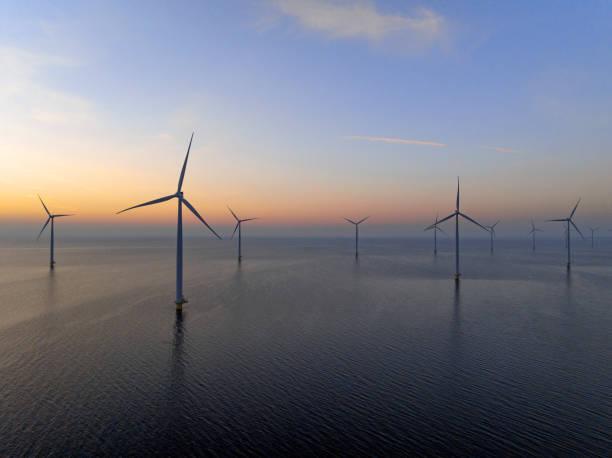 istock Wind turbines in an offshore wind park producing electricity during sunset. 1389650011