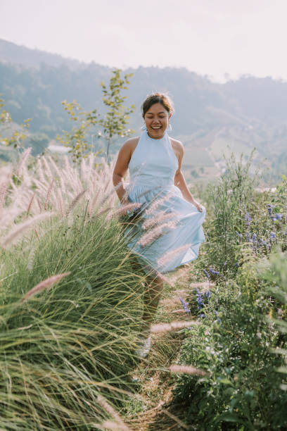 istock Thai woman is walking in flower field 1389650821