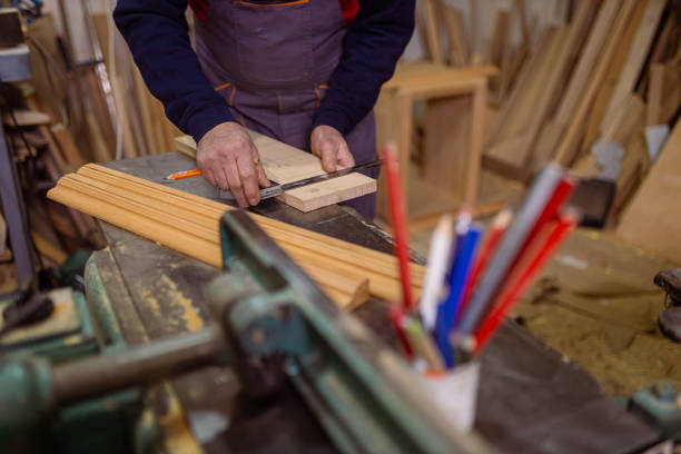 From his workshop, unrecognizable male carpenter with pen marks the design on the timber