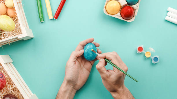istock hand painting colorful easter eggs on blue background 1389652436