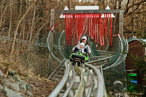 Mother with daughter ride electric sleigh on rails.