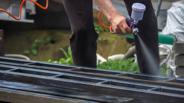 istock A man with a paint sprayer paints a metal structure on the street. 1389653372
