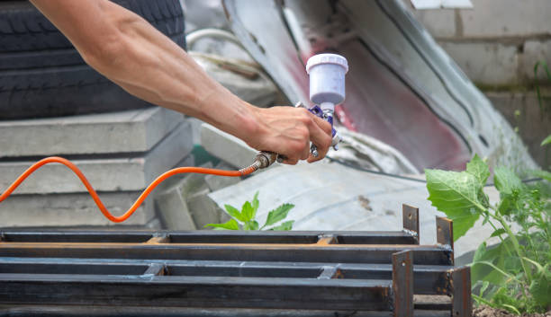istock A man with a paint sprayer paints a metal structure on the street. 1389653374
