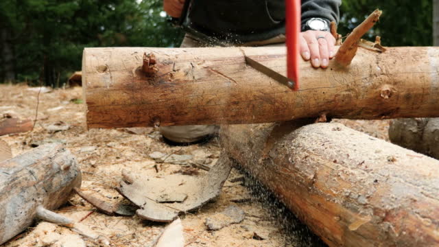 People using a hand saw to cut a piece of wood the old way stock video