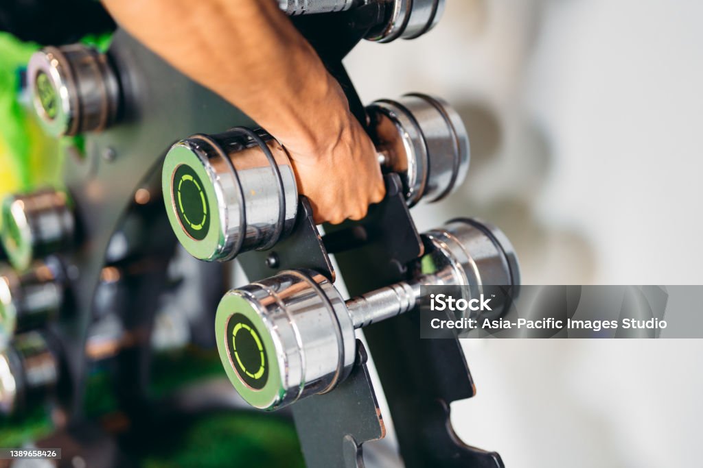 Close up of unrecognizable man taking dumbbells in a gym.  Health and fitness concept. Barbell Stock Photo