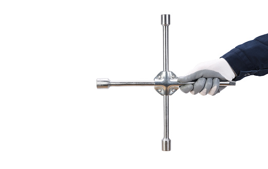 A worker's hand holds a cross-shaped gas wheel wrench on a white background.