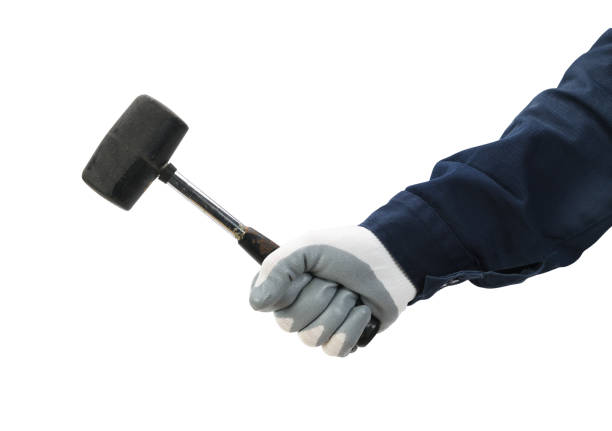istock Hand of a worker with a rubber mallet in his hand isolated on a white background. 1389658780