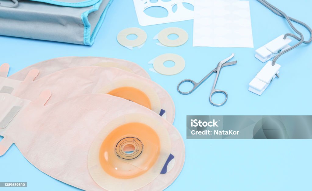 Set of colostomy bag on a blue background. Three colostomy bags with medical scissors, a stencil of different diameters, a sticky circle, a bag and clothespins on a rope lie on a soft blue background, close-up side view. Bag Stock Photo