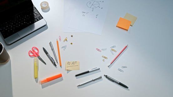 Overhead view of office supplies on wooden desk.