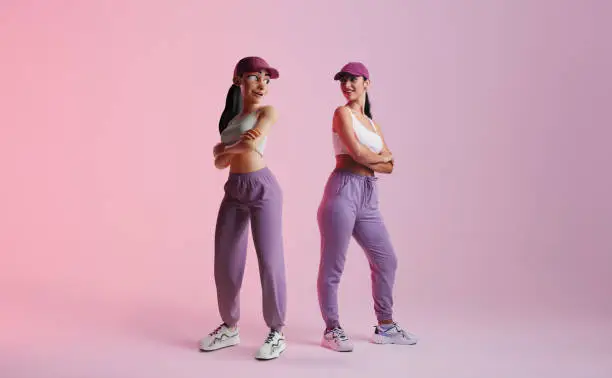 Happy young woman standing next to her metaverse avatar in a studio. Cheerful young woman smiling at the 3D simulation of herself. Young woman exploring virtual reality.