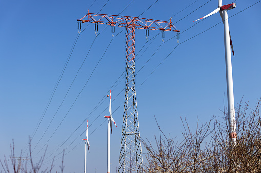 German wind turbines and overhead power lines under a blue sky