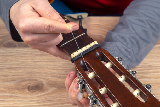 istock replacement and insertion of nylon strings in a classical guitar. lesson for a musician 1389666671
