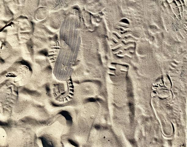istock Shoe Sole Prints in Beach Sand 1389668090