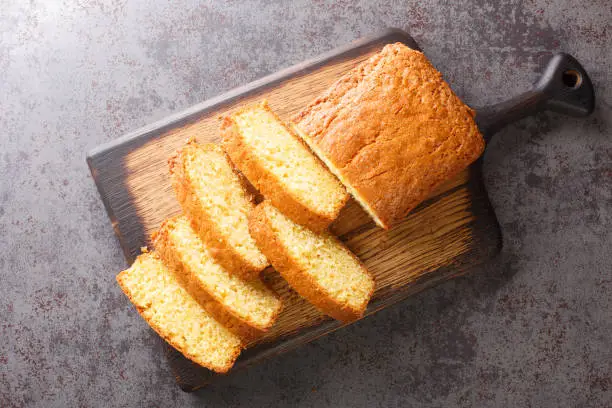 Photo of Delicious tender Madeira biscuit cake close-up on a wooden board. horizontal top view
