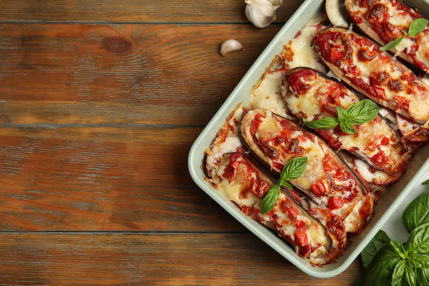 berenjena al horno con tomates, queso y albahaca en vajilla sobre mesa de madera, puesta plana. espacio para texto - aubergines parmesan fotografías e imágenes de stock