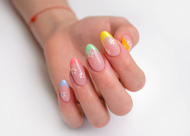 mani di una giovane donna con una manicure. le unghie sono ricoperte di smalto gel con francesi colorati e fiori - woman of color foto e immagini stock