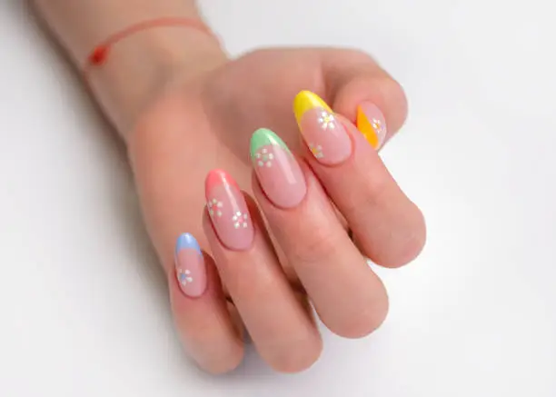 Hands of a young woman with a manicure. The nails are covered with gel polish with colored French and flowers