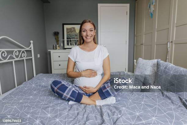 Pregnant Woman In Pajamas On Bed At Home Stock Photo - Download Image Now - Baby - Human Age, Bumpy, Human Abdomen