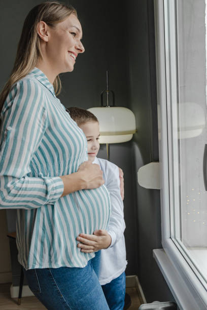 istock Pregnant woman standing by the window 1389674524