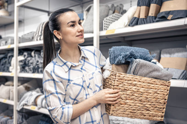 una joven con una cesta de mimbre llena de mantas en una tienda de mejoras para el hogar. - wicker basket store gift shop fotografías e imágenes de stock