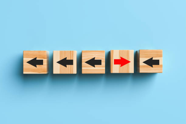 istock Wooden blocks with arrows with one stand out from the crowd and move forward on blue background. 1389677868