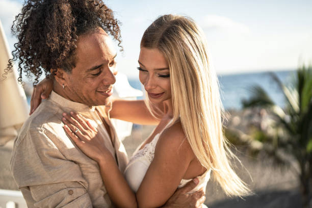 pareja romántica multiétnica bailando juntas en una cita al aire libre. día soleado de verano. - honeymoon beach couple heterosexual couple fotografías e imágenes de stock