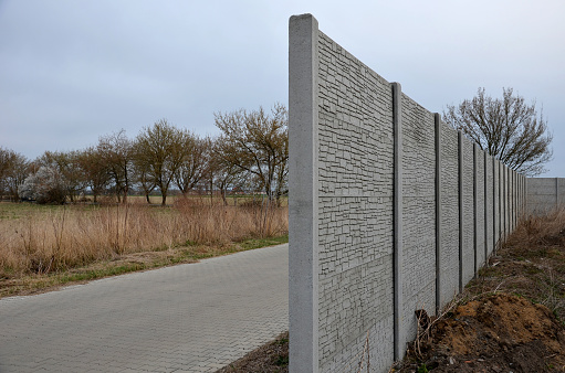 soundproof wall made of concrete porous ribbed material. fence of gray blocks embedded in metal beams, on street. road traffic noise  garden and residential area. protection of Jerusalem, rocket, panel
