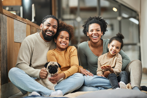 Happy black parents with their small girls and a dog spending time at home.