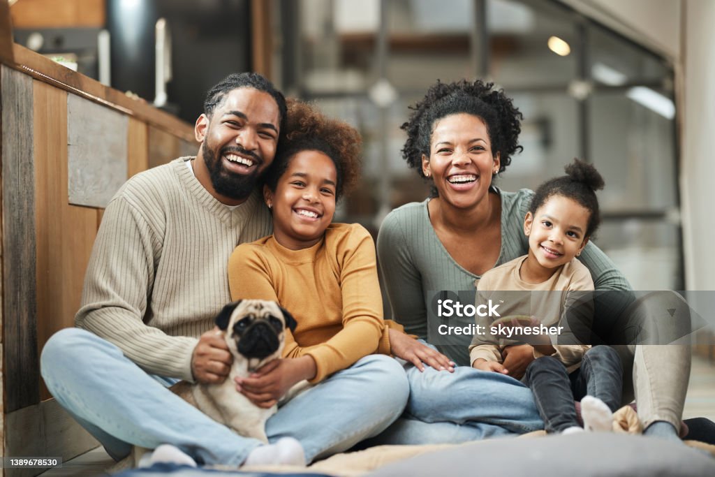 Happy African American family and their dog enjoying at home. Happy black parents with their small girls and a dog spending time at home. Family Stock Photo
