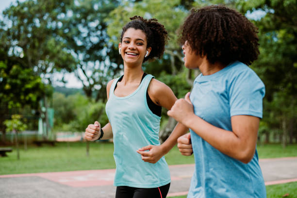 2人の10代の女の子の友人が走って、運動する - running jogging african descent nature ストックフォトと画像