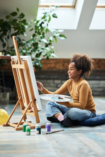 幸せなアフリカ系アメリカ人の創造的な女の子は自宅で絵を描いています。 - artists canvas indoors childhood small ストックフォトと画像