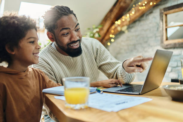 istock Happy single black father and son using laptop at home. 1389679590