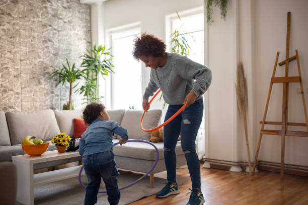 madre e hijo jugando con hula hoop en la sala de estar - hooping fotografías e imágenes de stock