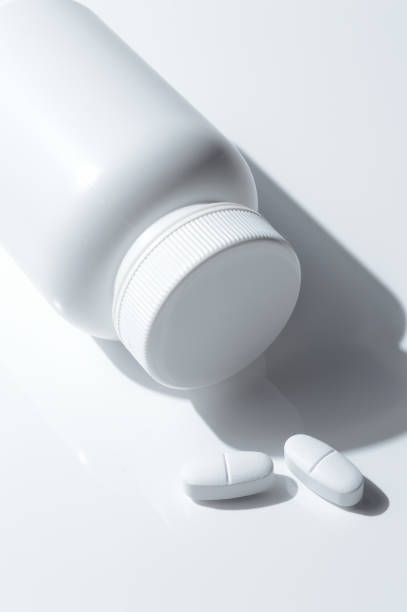 istock white plastic medicine jar and two white pills. light background. 1389683194