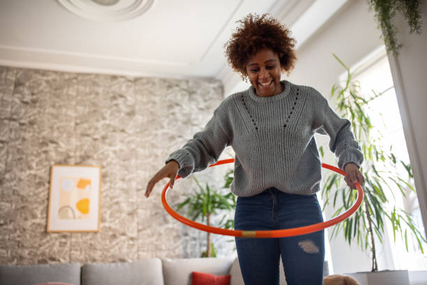 mujer etnia negra girando el hula hoop alrededor de su cintura - day in the life fotografías e imágenes de stock