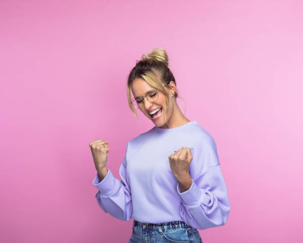 cheerful woman with clenched fists - women standing fist success imagens e fotografias de stock