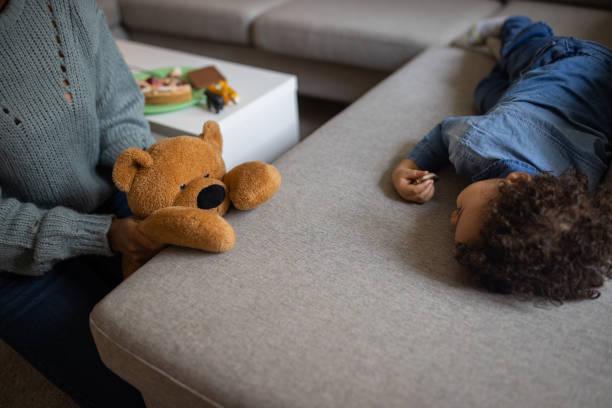 Mixed-race toddler boy lying on the sofa and eating chocolate