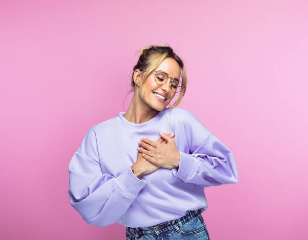 Happy woman keeping hands on heart stock photo