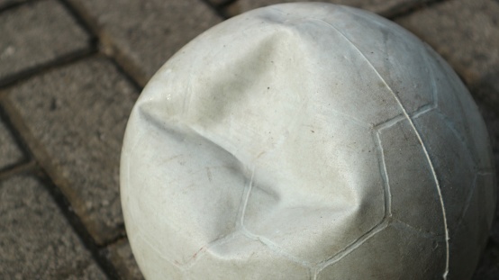 dented (broken) plastic ball on the paving block. Close up.