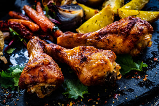 istock Barbecue chicken drumsticks with potatoes and vegetables on black wooden table 1389683789