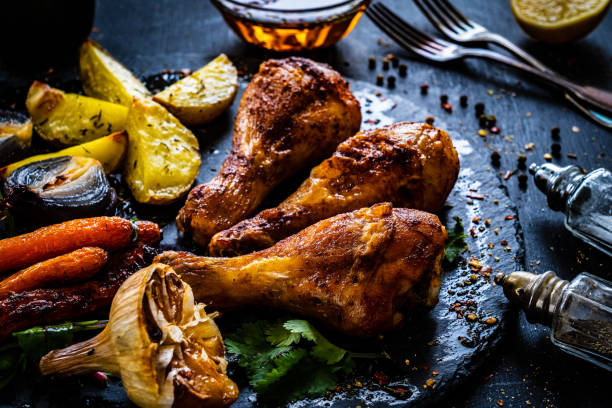 istock Barbecue chicken drumsticks with potatoes and vegetables on black wooden table 1389683839