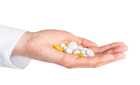 Human hand holding pills isolated on white background. Pharmacy, pharmacology, medicine background. Clipping path