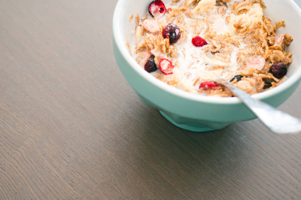 Bowl of muesli isolated on dark wooden background. Fresh oats with fruits and milk for healthy breakfast.