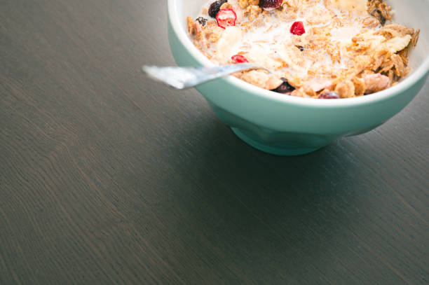Bowl of muesli isolated on dark wooden background. Fresh oats with fruits and milk for healthy breakfast.