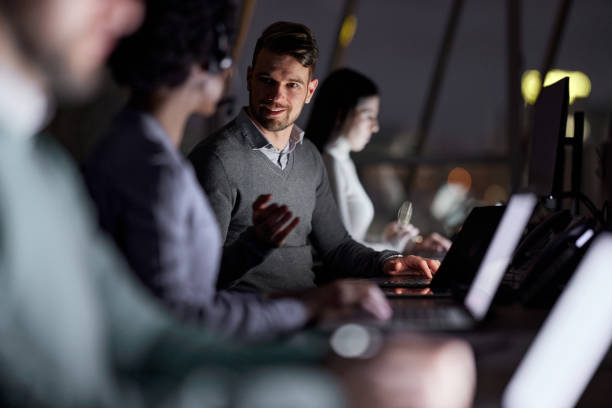 istock Business colleagues talking while working on laptops late in the office. 1389684678