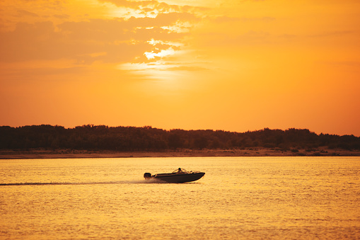 Speedboat with fishers at the river at sunset